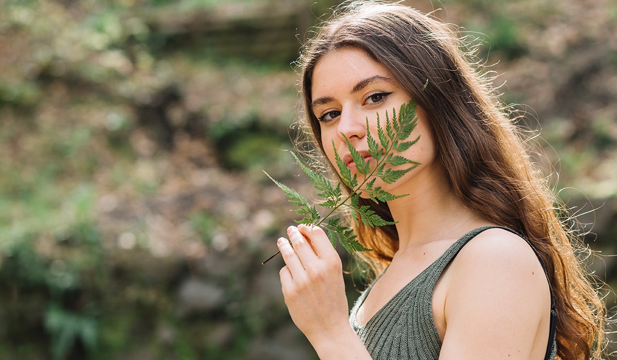young woman smelling leaf forest